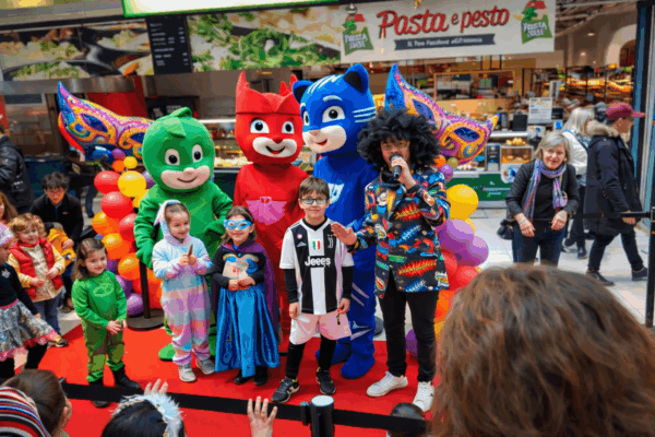 Mascotte americane animate da attori professionisti coinvolgono bambini e famiglie durante un evento di piazza, creando un momento di festa, interazione e divertimento per tutte le età